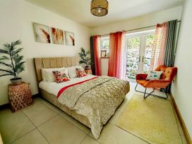 A bedroom with a bed and chair at 4 Bed Villa Sleeps 8 Private Terrace Free parking Near St Austell