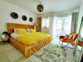 A bedroom with a yellow bed and an orange chair at 4 Bed Villa Sleeps 8 Private Terrace Free parking Near St Austell