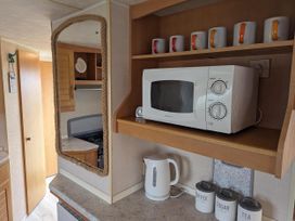 A kitchen with a microwave and mugs at Sandy Paws Dog Friendly Anderby Creek