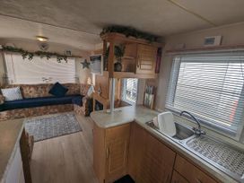 A living room with a sofa and kitchen counter at Sandy Paws Dog Friendly Anderby Creek