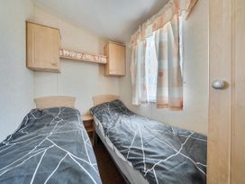 A bedroom with two single beds and a shelf above at 3 Bed Caravan Sleeps 8 Pets Garden Parking Hull