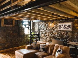 A living room with a sofa and spiral staircase at The Milking Shed at Pencraig Pet Friendly Llanynghenedl near Holyhead