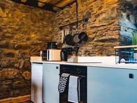 A kitchen with a countertop, microwave, and pots on the wall at The Milking Shed at Pencraig Pet Friendly near Holyhead