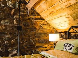 A bedroom with stone walls and wooden ceiling at The Milking Shed at Pencraig Pet Friendly near Holyhead