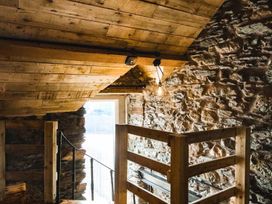 A loft area with wooden beams and stone wall at The Milking Shed at Pencraig Pet Friendly Llanynghenedl near Holyhead