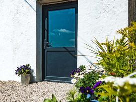 An entrance door with flowers in pots at The Milking Shed at Pencraig Pet Friendly near Holyhead