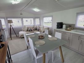 A kitchen and living area with a dining table and sofa at Luxury Cosy Caravan in Cresswell Northumberland