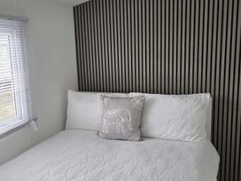 A bed with a decorative pillow against a striped wall at Luxury Cosy Caravan in Cresswell Northumberland