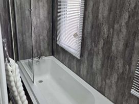 A bathroom with a bathtub and shower screen at Luxury Cosy Caravan in Cresswell Northumberland