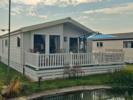 A mobile home with a deck and chairs at a property near a pond