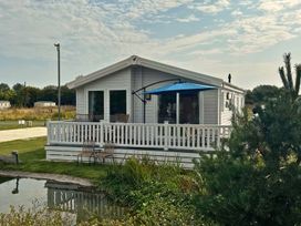A house with a deck and chairs at a garden with a pond