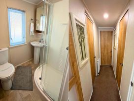 A bathroom with a shower and sink beside a hallway with doors at  