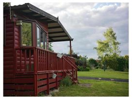 A red cabin with a deck and garden space at The Old Barn in Builth Wells