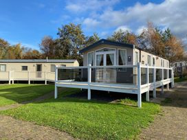 A caravan with a deck and grassy area at the holiday park