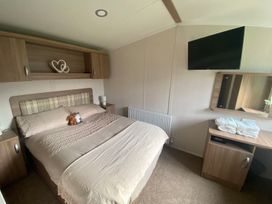 A bedroom with a bed, television, and dressing table at the property location