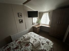 A bedroom with a bed, desk, and wall-mounted TV in a property