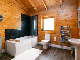 A bathroom with a bathtub, toilet, sink, and wooden features at a property