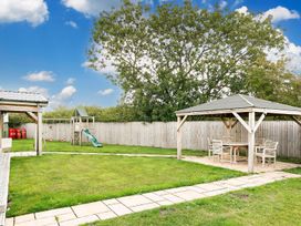 A garden with a playground, seating area and green grass at a property
