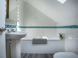 A bathroom with a sink, bathtub and mirror at Spacious 3 Bed House Sleeps 6 Parking Wifi in Newquay