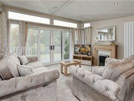 A living room with a sofa and television at 2Br Lodge Pool Fireplace PetsOK Parking in Goonhavern
