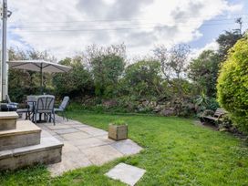 A garden with a table and chairs and an umbrella at Coastal Hideaway in Cornwall Dog Friendly Goldsithney