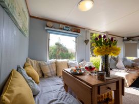 A snug with a sofa and table decorated with flowers at Coastal Hideaway in Cornwall Dog Friendly Goldsithney