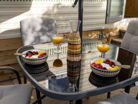 A table with bowls of fruit and drinks in an outdoor dining area at Coastal Hideaway in Cornwall Dog Friendly, Goldsithney