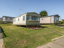 A mobile home with a flower bed and pathway at 3 Bed Sleeps 8 Sea View Pets Parking Reighton Gap near Filey