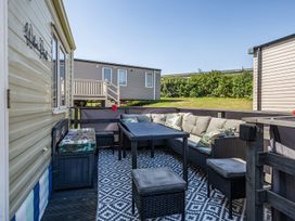 An outdoor seating area with a table and cushioned seats at 3 Bed Sleeps 8 Sea View Pets Parking Reighton Gap near Filey