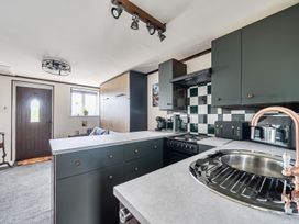 A kitchen with a stove, sink, and kitchen cabinets at Studio Sleeps 2 with Parking and Garden Trewidland near Liskeard