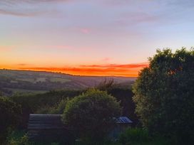 A sunset over hills and trees at Studio Sleeps 2 with Parking and Garden in Trewidland near Liskeard