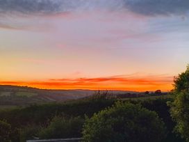 A scenic view of a sunset over hills and trees at Studio Sleeps 2 with Parking and Garden Trewidland near Liskeard