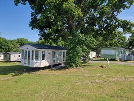 A static caravan next to a large tree at Thorness Bay