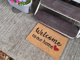A welcome mat and flower pot near garden steps at Chalet Sleeps 6 swimming pool Thorness Bay