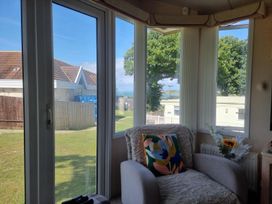A living room with a sofa and windows overlooking a lawn at Chalet Sleeps 6 swimming pool Thorness Bay