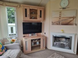 A living room with a television and a cabinet at Chalet Sleeps 6 swimming pool Thorness Bay