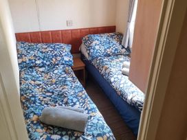 A bedroom with two single beds and a bedside table at Chalet Sleeps 6 swimming pool Thorness Bay