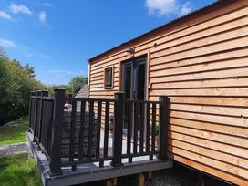 An outdoor area with a cabin exterior and balcony at Min yr Afon Cabin Sleeps2 Hot Tub Parking in Gwalchmai