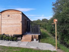 A cabin with a deck and garden features at Min yr Afon Cabin Sleeps2 Hot Tub Parking in Gwalchmai
