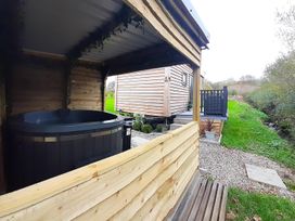 An outdoor area with a hot tub and wooden cabin at Min yr Afon Cabin Sleeps2 Hot Tub Parking in Gwalchmai