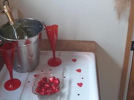 A champagne bottle in an ice bucket with red glasses and chocolates at Min yr Afon Cabin  Sleeps2  Hot Tub Parking Gwalchmai