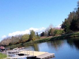 A river with a dock and trees at Selfcatering Lodge Inverness Sleeps 4 Inverness