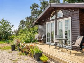A cabin with a deck, table, and chairs at Alpaca Farm Valley Views Sleeps 4 Parking Pets in Husthwaite