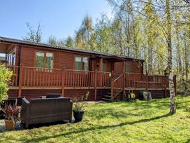 A lodge with a deck and garden furniture at Felmoor Park Northumberland Lodge with Hot Tub near Felton