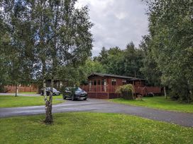 A lodge with cars parked on a driveway at Felmoor Park Northumberland Lodge with Hot Tub Felmoor Park near Felton