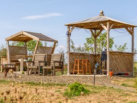 An outdoor seating area with a gazebo and wooden chairs at Cosy Luxury Owls Roost Hut with Private Hot Tub Little Deptford Farm near Umberleigh