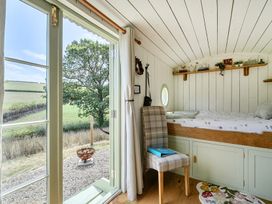 A bedroom with a bed and chair at Cosy Luxury Owls Roost Hut with Private Hot Tub near Little Deptford Farm near Umberleigh
