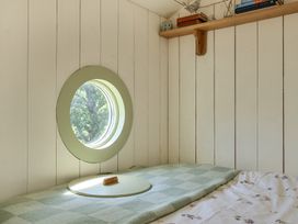 A bedroom with a round window and a bed at Cosy Luxury Owls Roost Hut with Private Hot Tub near Little Deptford Farm near Umberleigh
