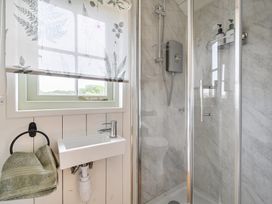 A bathroom with a shower and sink at Cosy Luxury Owls Roost Hut with Private Hot Tub near Little Deptford Farm