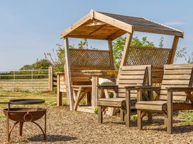 An outdoor seating area with a gazebo, table, and chairs at Cosy Luxury Owls Roost Hut with Private Hot Tub, Little Deptford Farm near Umberleigh